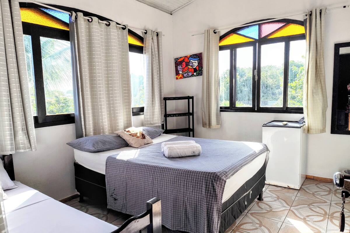 A room with a bed, a desk, and a window with curtains.