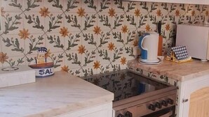 Une cuisine avec des armoires blanches, un fourneau et un dosseret carrelé orné d’un motif floral.