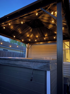 Un espacio al aire libre cubierto con techo metálico y luces colgantes.