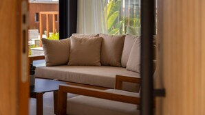 A modern living room with a beige sofa, a wooden coffee table, and a view of greenery outside. - Designer Bungalow with Private Infinity Pool in Paphos (Chlorakas)