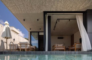 A modern outdoor pool area with lounge chairs and a covered seating area.