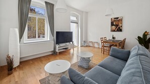Una sala de estar moderna con sofá, televisión, mesa de comedor y sillas.