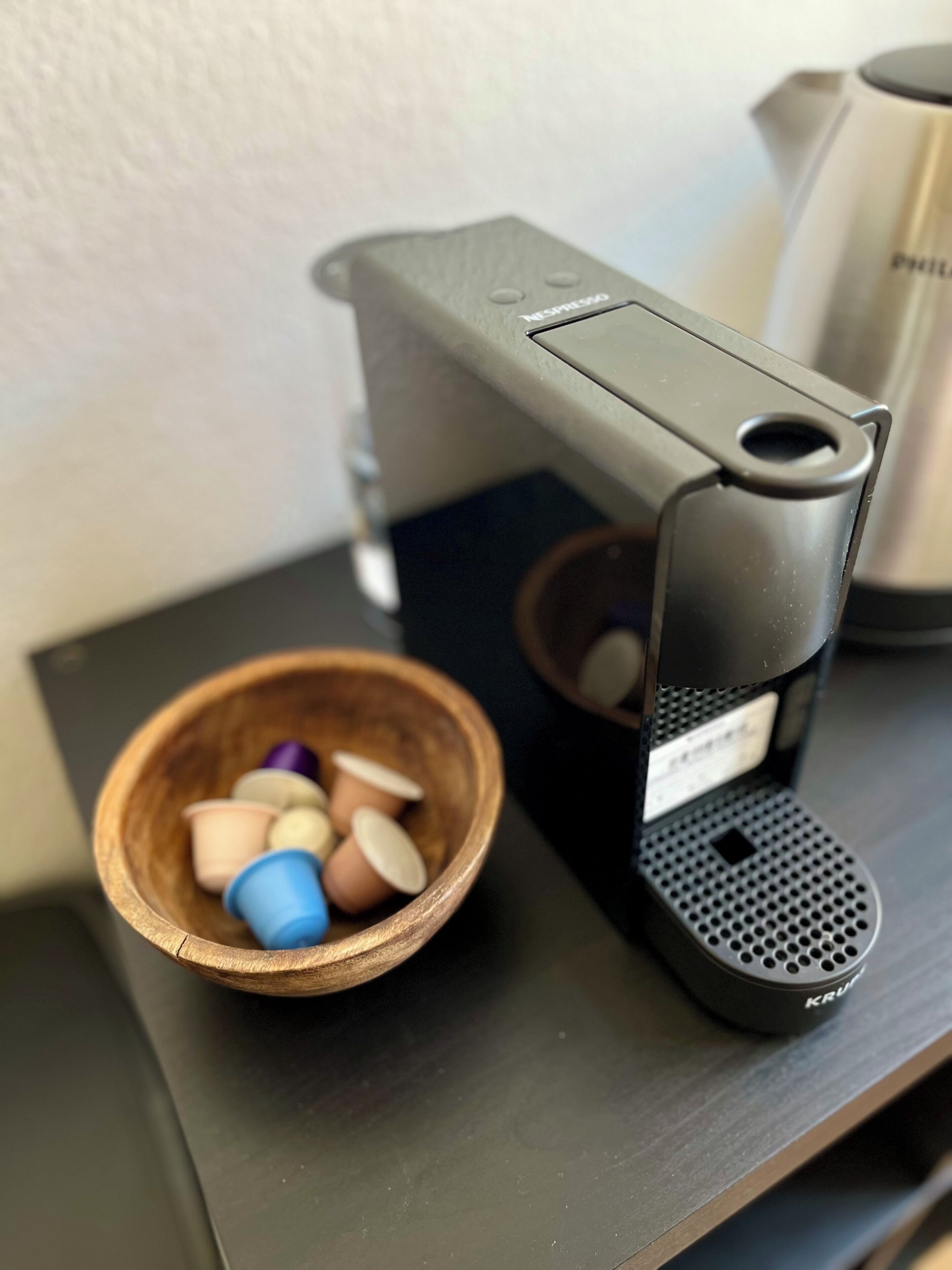 Uma máquina de café com uma tigela de cápsulas de café sobre uma prateleira.