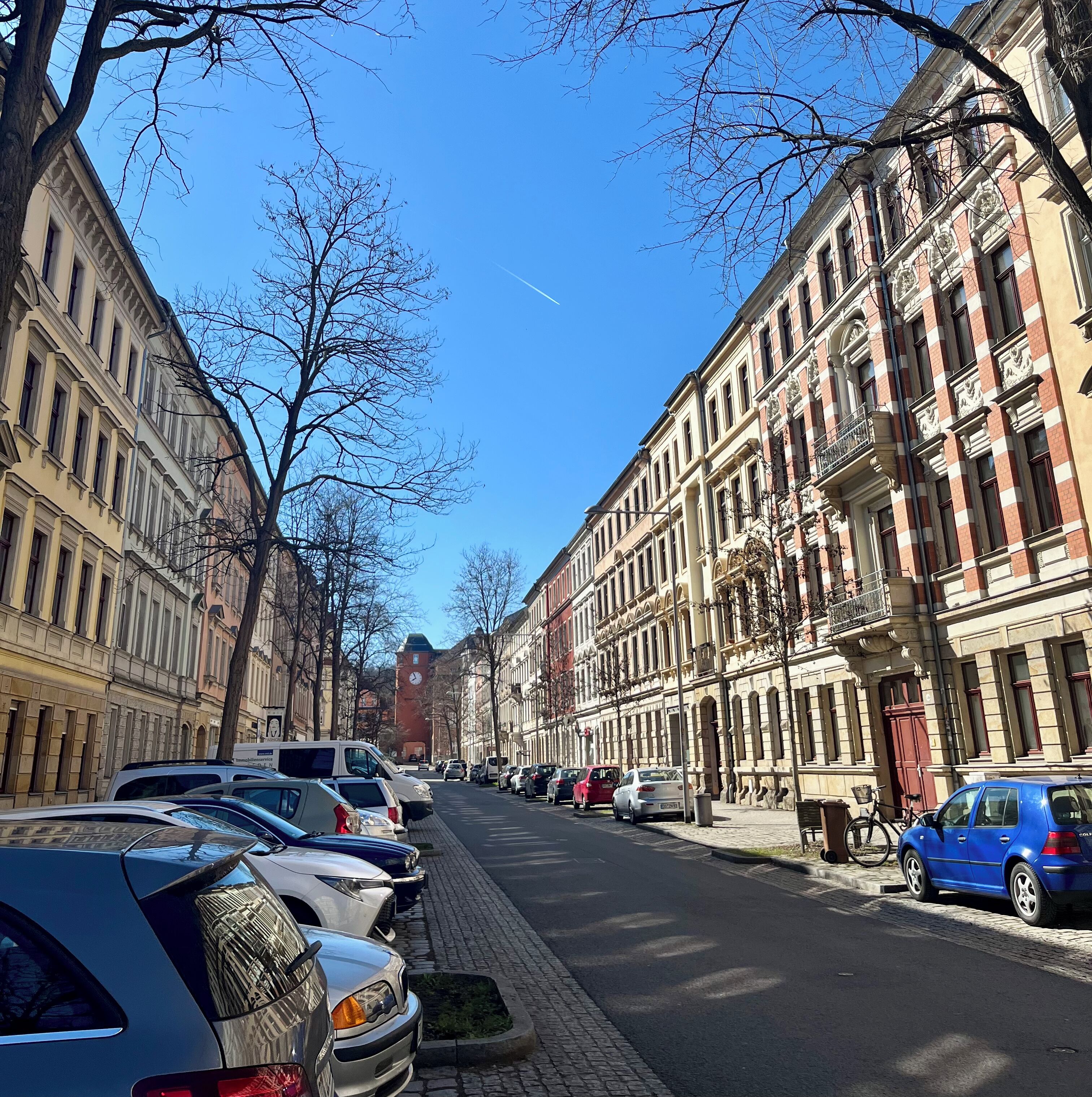 A street lined with parked cars and historic buildings.