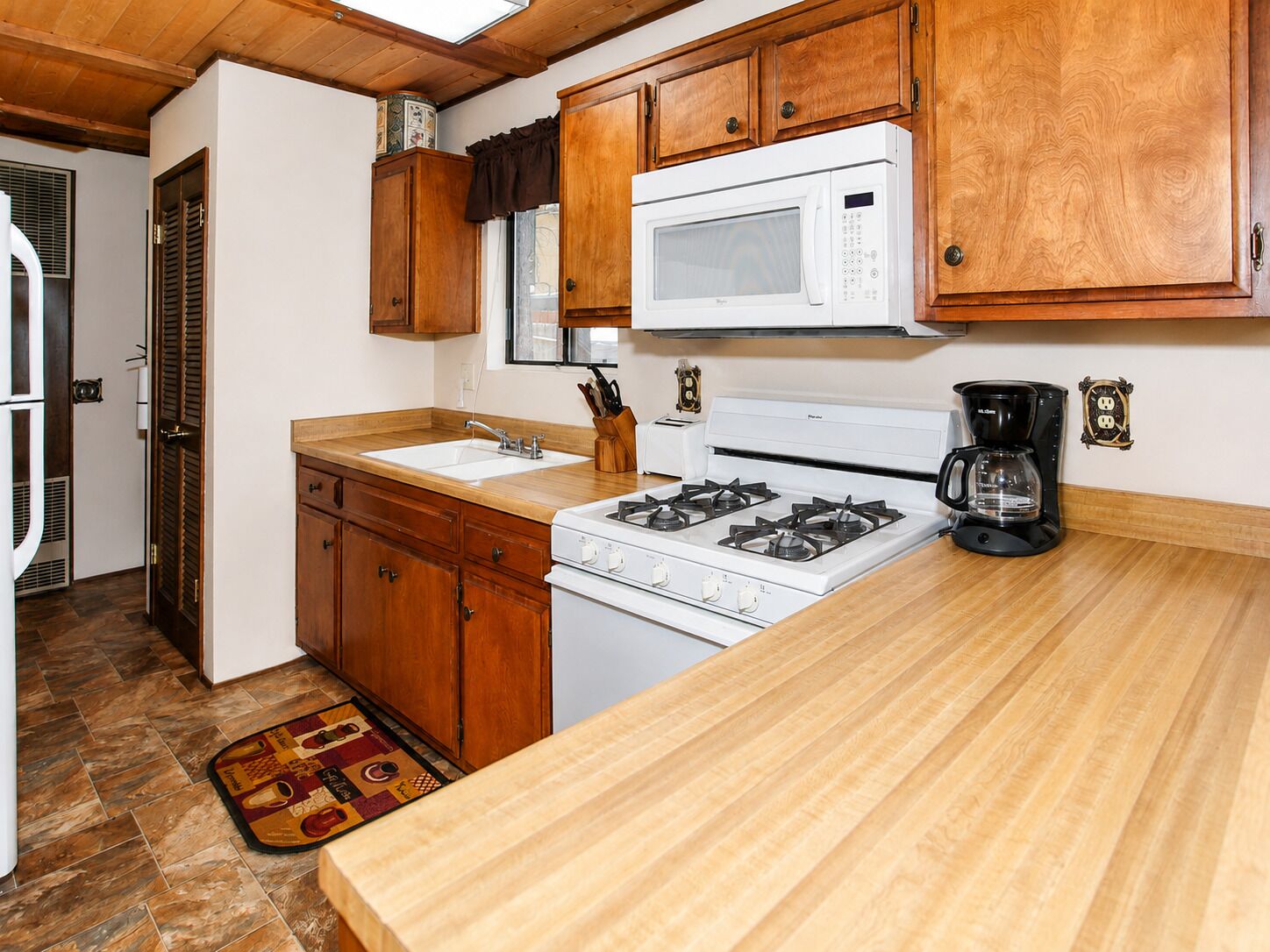 Una cocina con armarios de madera, estufa blanca, microondas y cafetera.