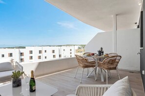 A balcony with a table set for two, wicker chairs, a bottle of champagne, and a potted plant. - Estepona Beach Getaway! 2BR Apartment (Estepona)