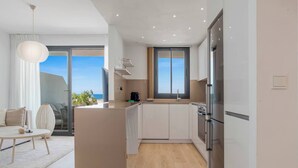 A modern kitchen with a central island, large windows, and a view of the sea. - Estepona Beach Getaway! 2BR Apartment (Estepona)