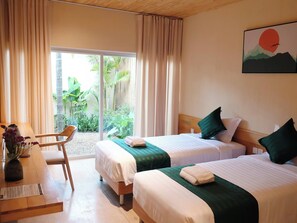 A hotel room with two beds, a wooden desk, a chair, and a view of greenery outside. - Va Riverside Retreat (Hue)