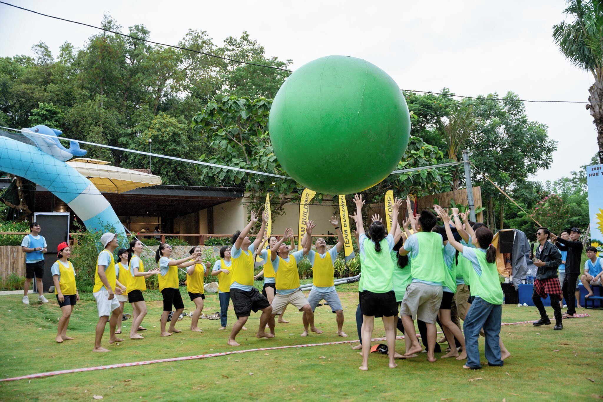 Een groep mensen neemt deel aan een activiteit buiten met een grote groene bal.