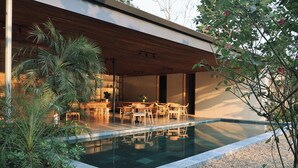 Ein moderner Außenpoolbereich mit Holzterrasse und Sitzgelegenheiten, umgeben von viel Grün.