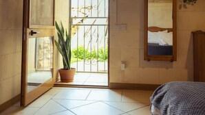 A room with a large sliding door leading to an outdoor area, a potted plant, a bed, a mirror, and a ceiling fan. - Serene Country House for Beach and Trekking Lovers (Xagħra)