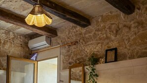 A bedroom with a bed, a dresser, a mirror, and a hanging light fixture. - Serene Country House for Beach and Trekking Lovers (Xagħra)