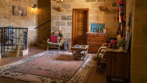 A rustic stone-walled room with a wooden door, a wicker chair, a wooden dresser, and a patterned rug. - Serene Country House for Beach and Trekking Lovers (Xagħra)