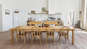 A spacious kitchen with a wooden dining table and chairs, white cabinets, and a brick backsplash. - Salt Creek Atelier, a luxuriously cozy loft in downtown Ashland NE. (Ashland)