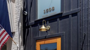A wooden door with a glass panel, a brass bell above it, and a sign above the door reading "1508 SILVER STREET SCATELIER EST. 2024". - Salt Creek Atelier, a luxuriously cozy loft in downtown Ashland NE. (Ashland)