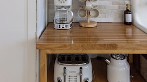 A kitchen with a coffee maker, toaster, and a bottle of hand sanitizer on the counter. - Salt Creek Atelier, a luxuriously cozy loft in downtown Ashland NE. (Ashland)