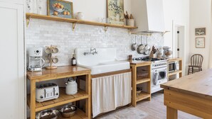 A compact kitchen with white appliances, wooden shelves, and a white brick backsplash. - Salt Creek Atelier, a luxuriously cozy loft in downtown Ashland NE. (Ashland)