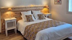A bedroom with a wooden headboard, white bedding, patterned throw, bedside tables with lamps, and a framed picture on the wall. - Family home in the heart of the Arcachon basin in Gujan Mestras (Gujan-Mestras)