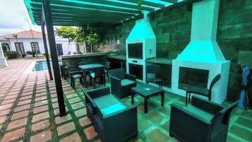 An outdoor patio with a grill, seating, and a pool.