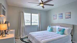 Un dormitorio con cama, ventilador de techo, ventana con cortinas y decoración en la pared.