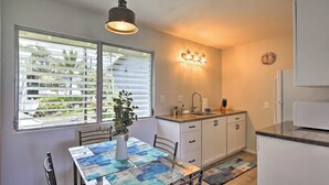 Cocina pequeña con una mesa de comedor, una planta y una ventana con persianas.