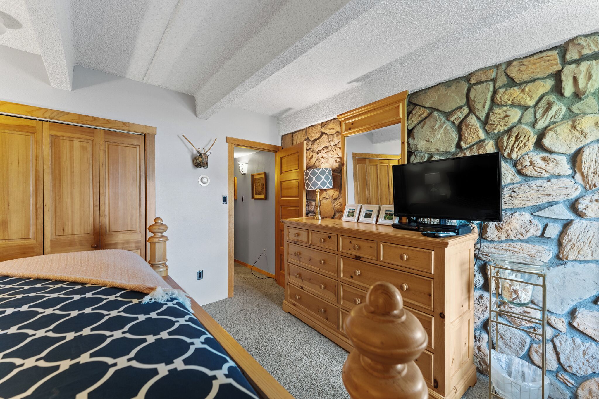 Una camera da letto con un letto, una cassettiera in legno e una televisione.