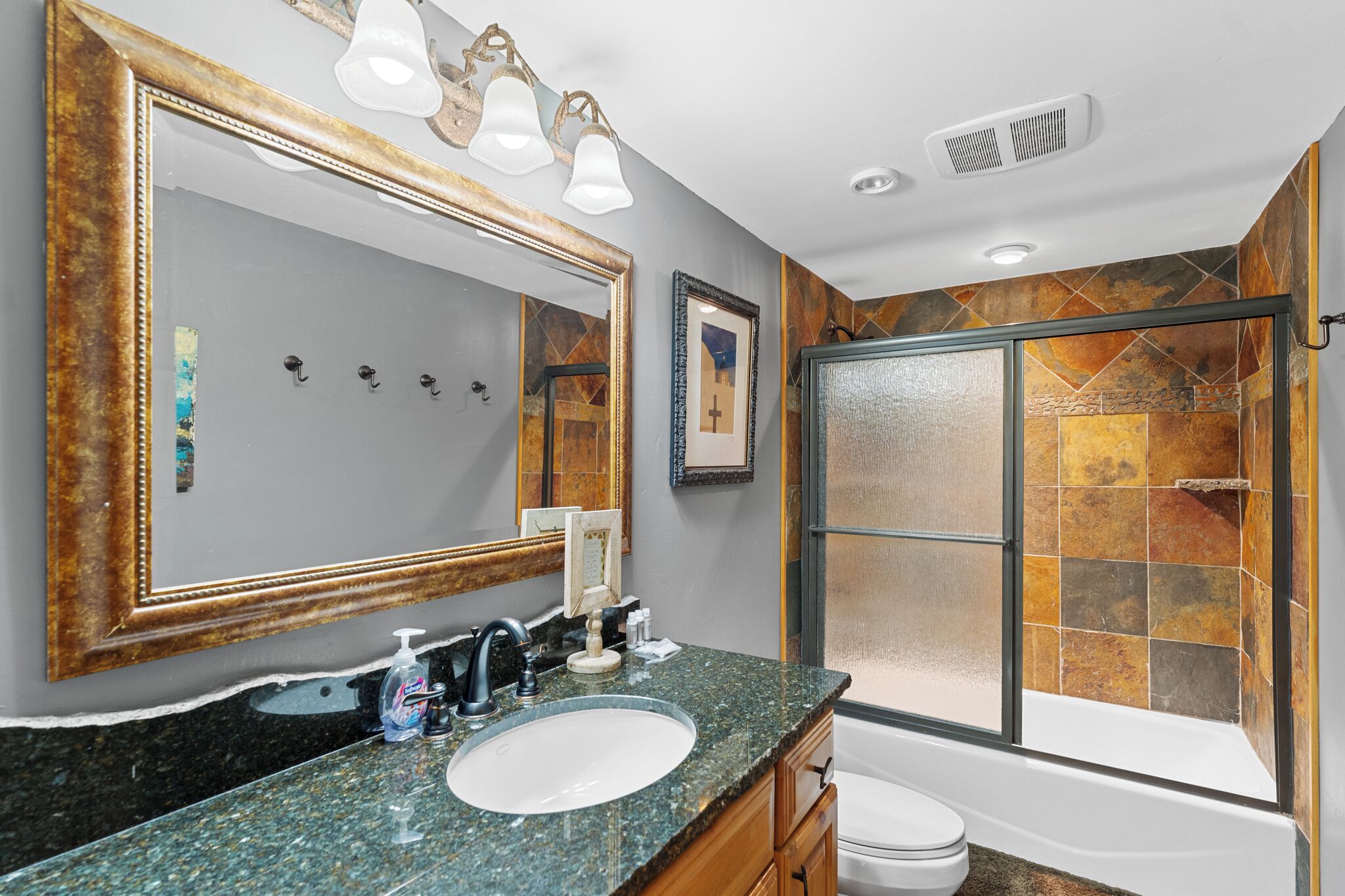 Un baño con un espejo grande, un lavabo, ducha con puerta de cristal y una bañera.