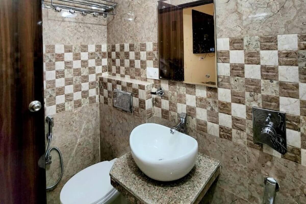 A bathroom with a marble wall, a sink, a toilet, and a shower.