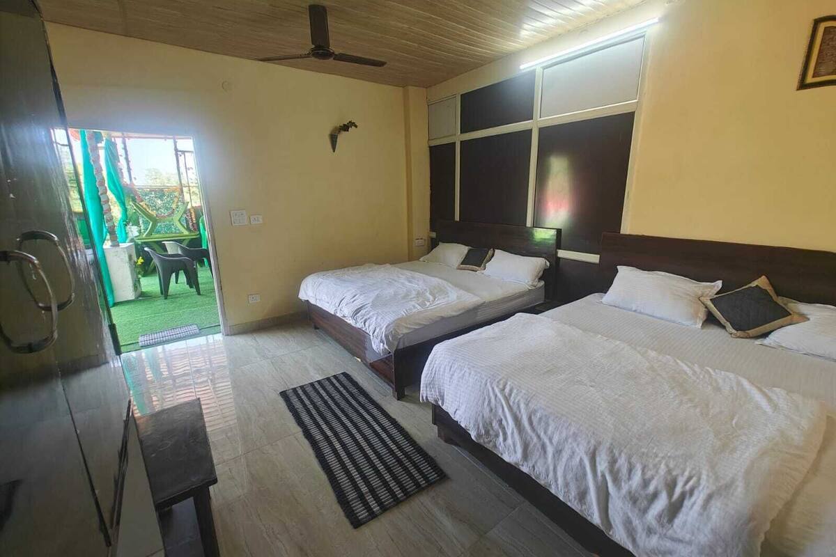 A hotel room with two beds, a ceiling fan, and a view of the outside.
