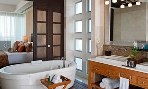 A modern bathroom with a freestanding bathtub, a vanity with a mirror, and a large window. - Beautiful Grand Luxxe 2-Bedroom Master Suite (Las Jarretaderas)