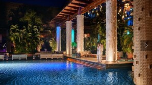 A pool area with a water feature, palm trees, and a covered seating area.