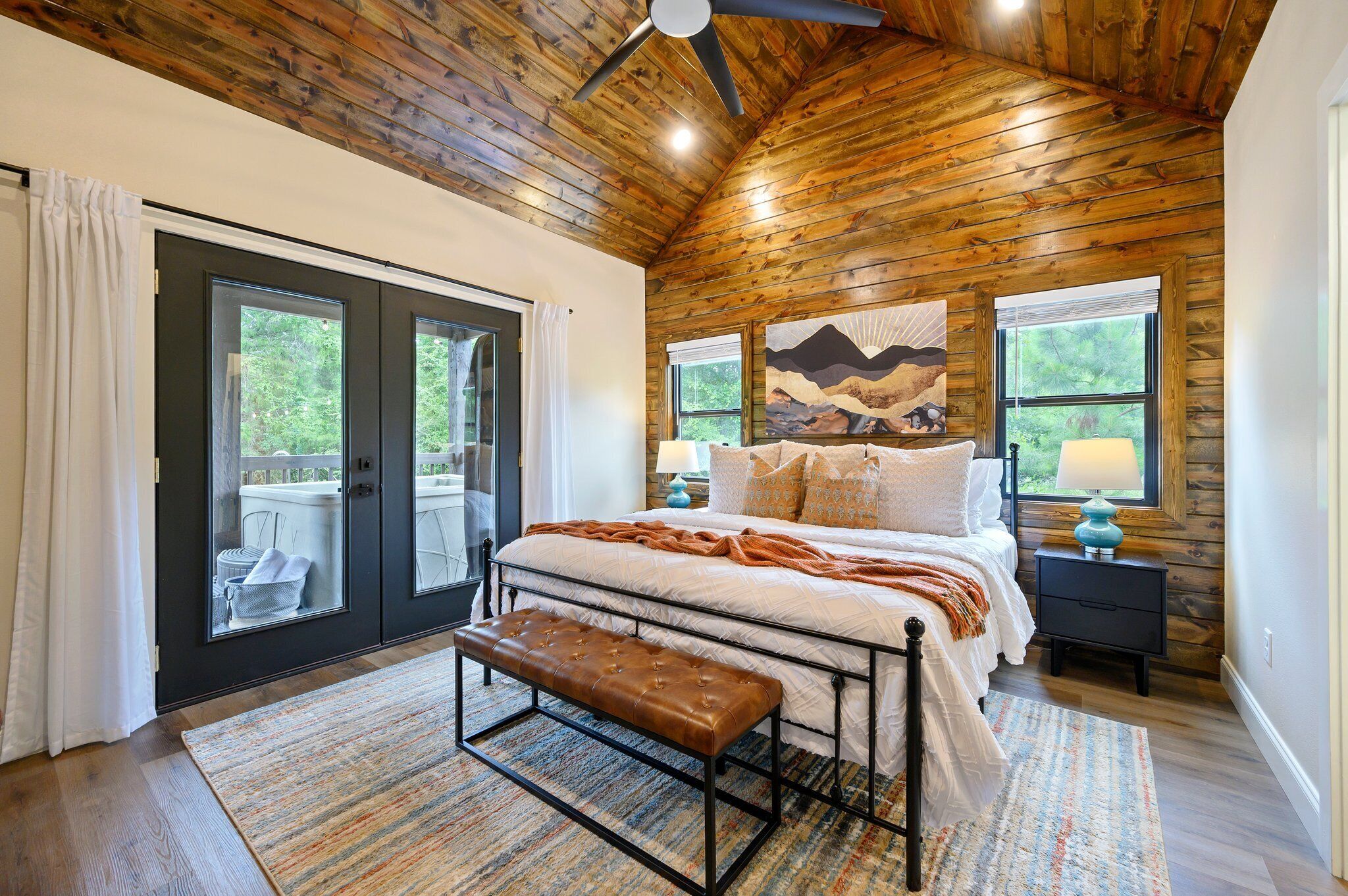 A bedroom with a bed, bench, and two windows.