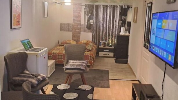 Un espace de vie compact comprenant un canapé, une petite table, un téléviseur et un lit.