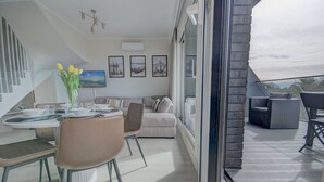 Una sala de estar moderna con comedor, un conjunto de sofás y vistas a través de un ventanal.
