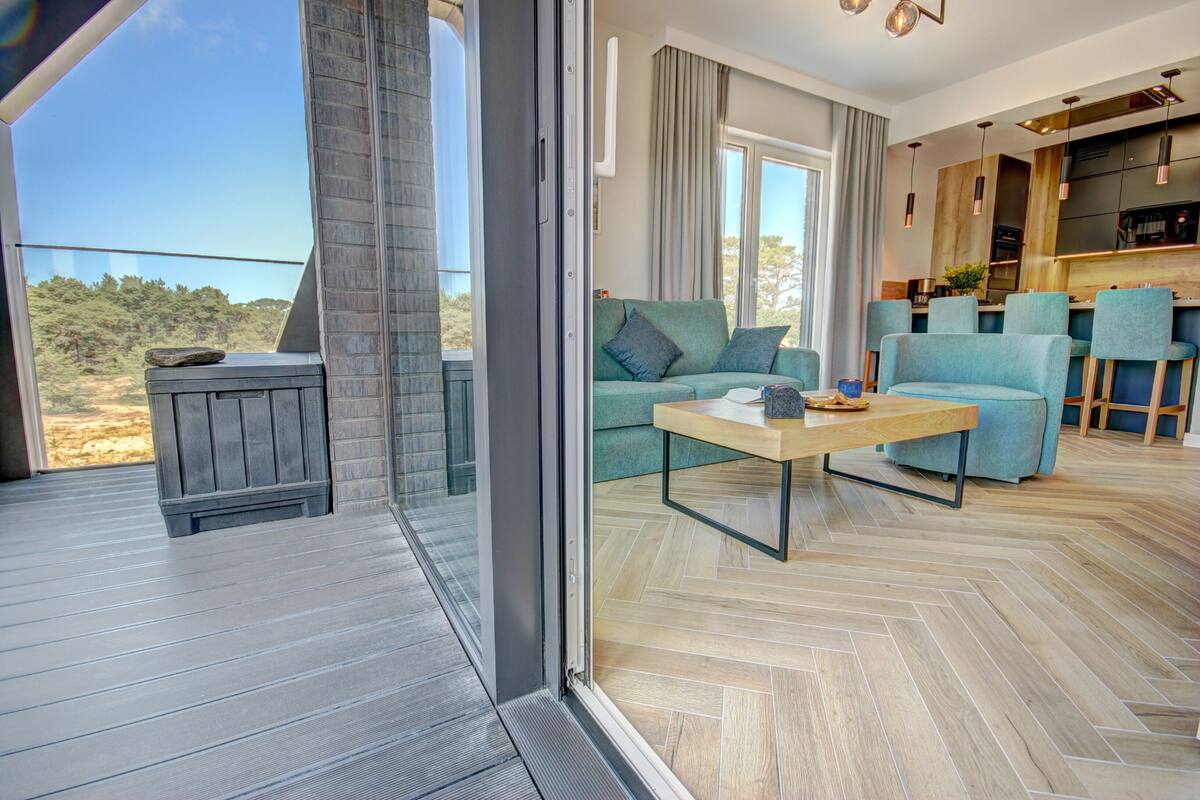 A modern living room with a sofa, coffee table, and a view of the outdoors.