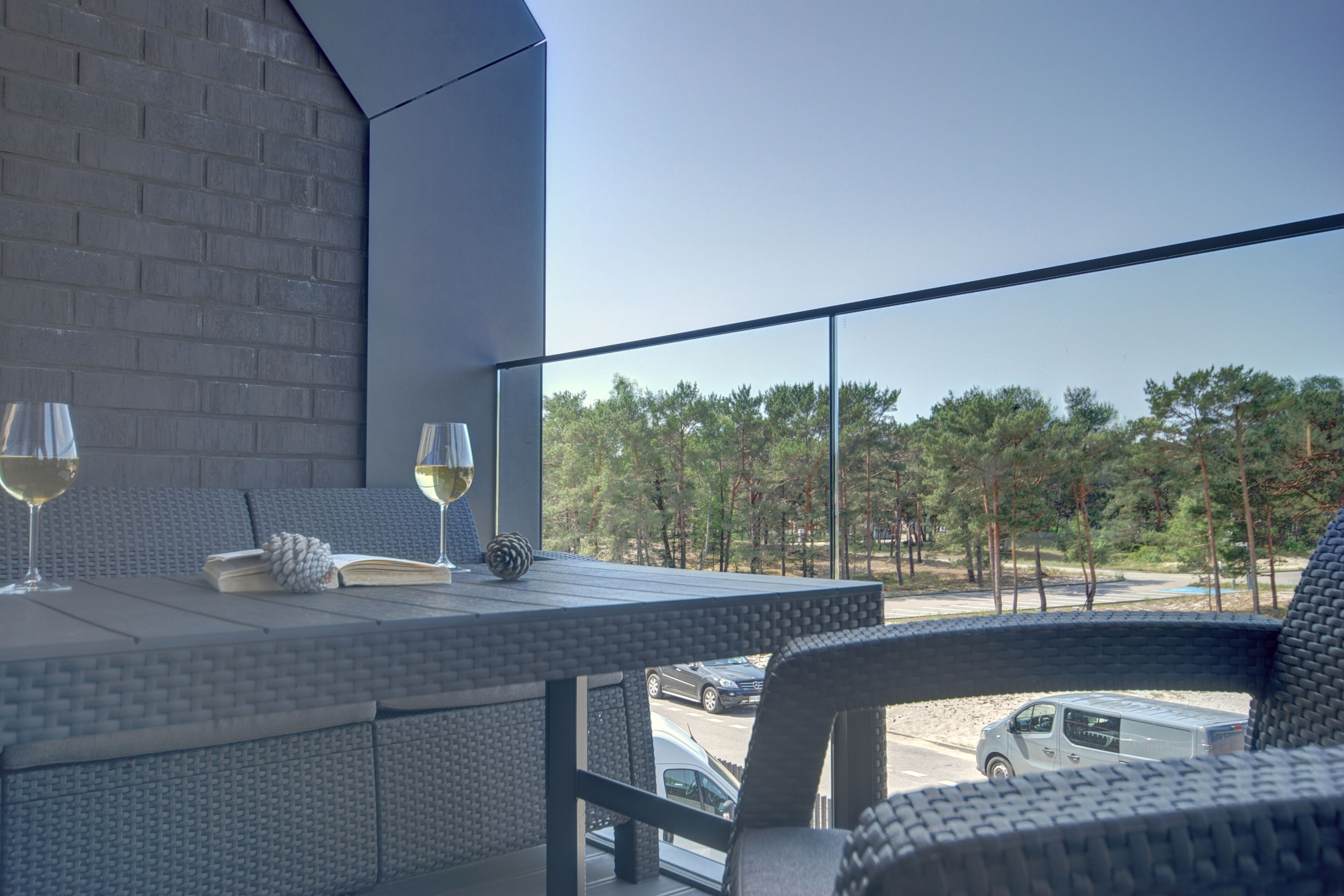 Un balcon avec une table dressée pour deux personnes, deux verres à vin et un livre.