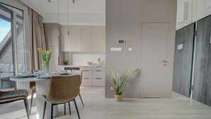 Una cocina moderna con armarios blancos, una mesa de comedor con sillas y una planta en maceta.