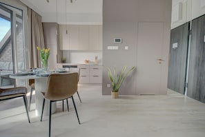 Una cocina moderna con armarios blancos, una mesa de comedor con sillas y una planta en maceta.