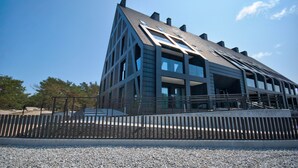 Un edificio moderno con techo inclinado, amplias ventanas y suelo de grava.