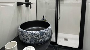 Un baño con un lavabo de estampado blanco y negro, una taza blanca y un pequeño jabonera.