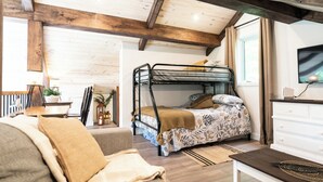 A cozy room with a bunk bed, a sofa, a TV, and a dining area with a table and chairs. - Aux Repères de Papi (Lac-Etchemin)