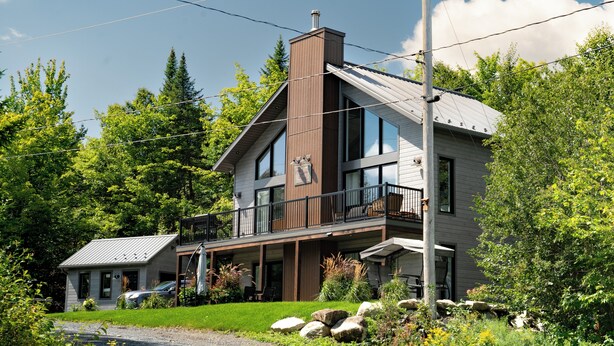 A modern two-story house with a balcony, large windows, and a garage. - Aux Repères de Papi (Lac-Etchemin)