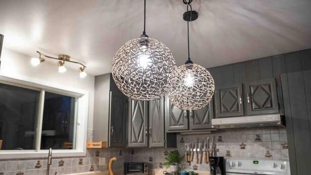 A modern kitchen with dark cabinets, a stainless steel sink, a microwave, and a stove. - Aux Souvenirs doux CITQ 303027 (Lac-Etchemin)