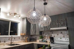 Una cocina moderna con armarios oscuros, un lavamanos de acero inoxidable, un microondas y una estufa.