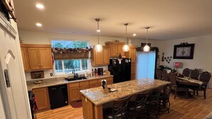 A modern kitchen with wooden cabinets, a central island, and pendant lighting.