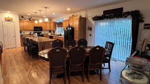 A spacious kitchen with wooden cabinets, a central island, and a dining area with dark wooden chairs.