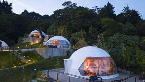 A dome-shaped structure with a glass exterior, situated on a raised platform with a surrounding deck. - CARDEDEU DOMOS (Santa Tecla)