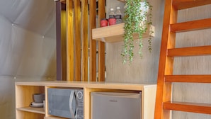 A compact kitchenette with a microwave, refrigerator, and a small cabinet with a lock. - CARDEDEU DOMOS (Santa Tecla)