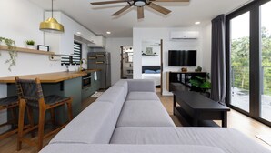 Um espaço de estar moderno com cozinha, sala de jantar e um sofá grande.