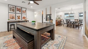 A modern dining area with a central table, chairs, and a ceiling fan.